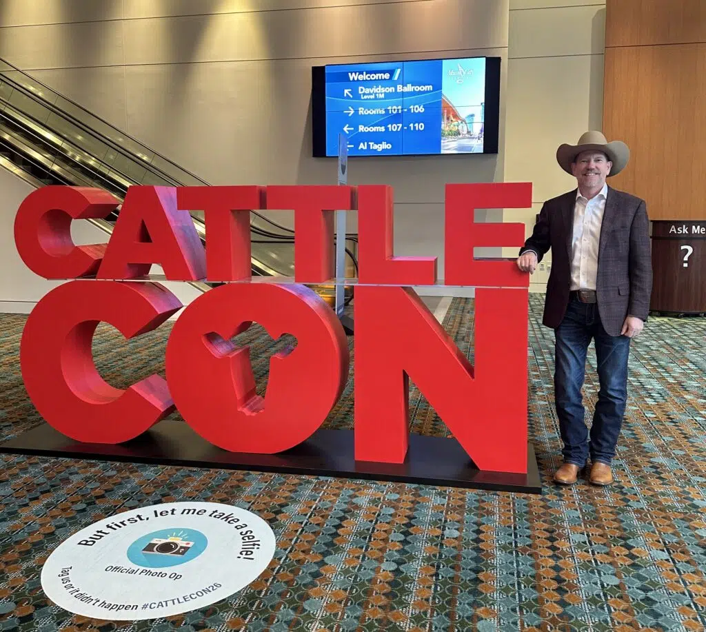 A Kincannon & Reed attendee standing by the CattleCon sign at CattleCon.